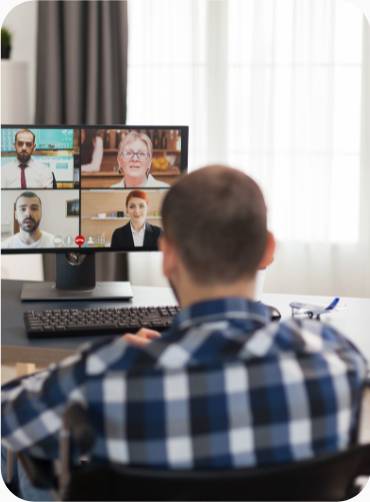 Back view of a man in a wheelchair working at a desk on a video call to four other people