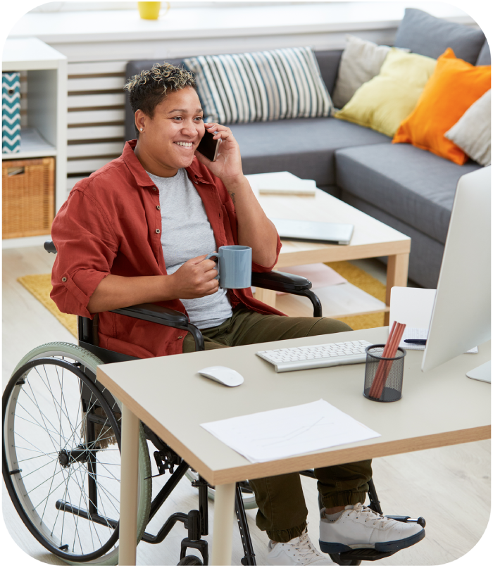 A woman in a wheelchair smiles on the phone while holding a mug