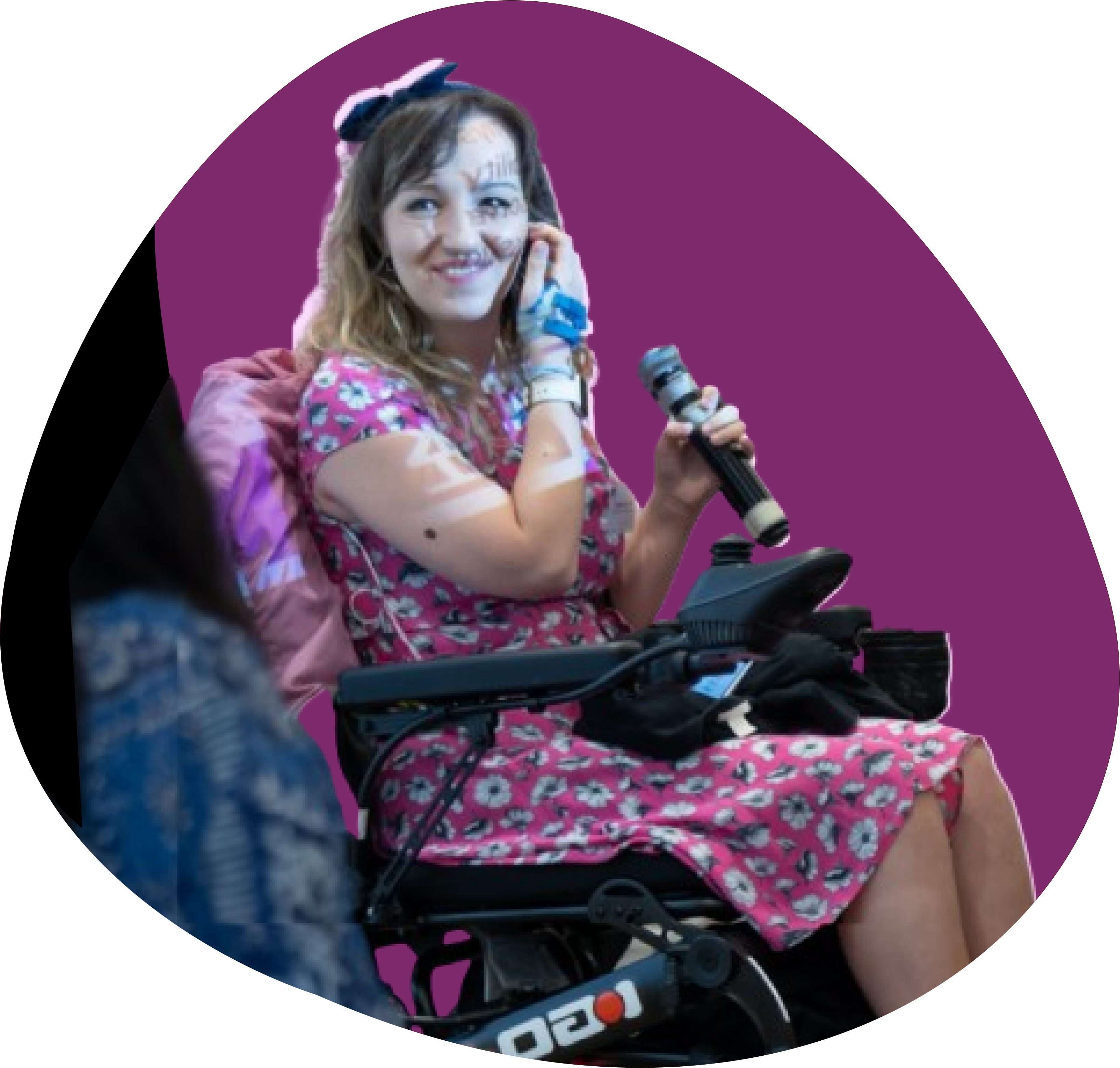 Patchwork Hub's founder Beth in her power chair holding a microphone at an Innovate UK event.